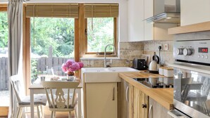 A kitchen with wooden cabinets, a stainless steel oven, and a window with a view of greenery. - 1 bedroom accommodation in Bittaford, near Ivybridge (Bittaford, near Ivybridge)