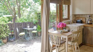 A cozy kitchen with a dining area, a wooden fence, and a view of the garden. - 1 bedroom accommodation in Bittaford, near Ivybridge (Bittaford, near Ivybridge)