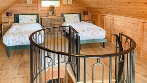 Un dormitorio acogedor en el ático con dos camas, techo de madera y una ventana pequeña.