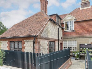 A traditional brick house with a tiled roof and a black metal fence.