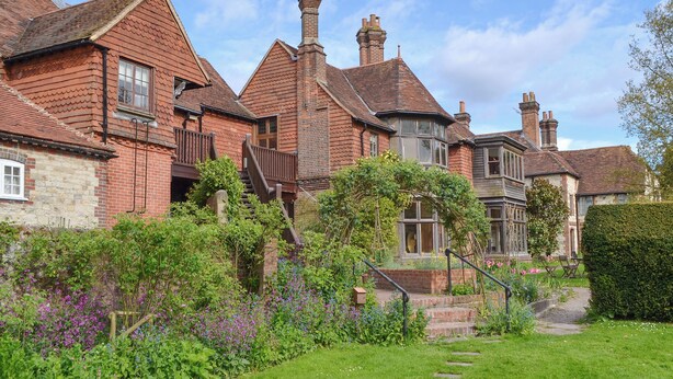 A traditional brick house with a red-tiled roof, a stone foundation, and a garden with various plants and flowers. - 3 bedroom accommodation in Selborne, near Alton (Selborne, near Alton)