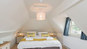 A bedroom with a bed, bedside tables, a hanging light fixture, a window with curtains, and a ceiling light. - 3 bedroom accommodation in Selborne, near Alton (Selborne, near Alton)