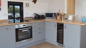 A modern kitchen with a built-in oven, microwave, and coffee maker. There is a wooden countertop and a view of the outside through a window. - 2 bedroom accommodation in Beccles, near Gillingham (Beccles, near Gillingham)