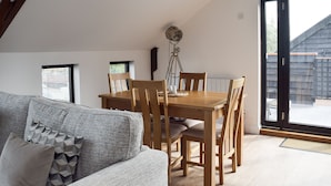 A dining area with a wooden table and chairs, a floor lamp, and a view of the outside through a large sliding door. - 2 bedroom accommodation in Beccles, near Gillingham (Beccles, near Gillingham)
