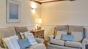 Ein gemütliches Wohnzimmer mit zwei beigen Sofas, einem Holztisch und einer Wandlampe.