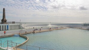 Une piscine agrémentée d’un monument, d’un escalier et offrant une vue sur la mer.