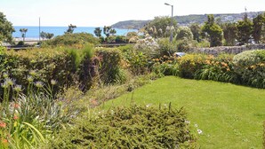 Un jardin luxuriant, avec une grande variété de plantes et de fleurs, une pelouse bien entretenue et un mur en pierre.