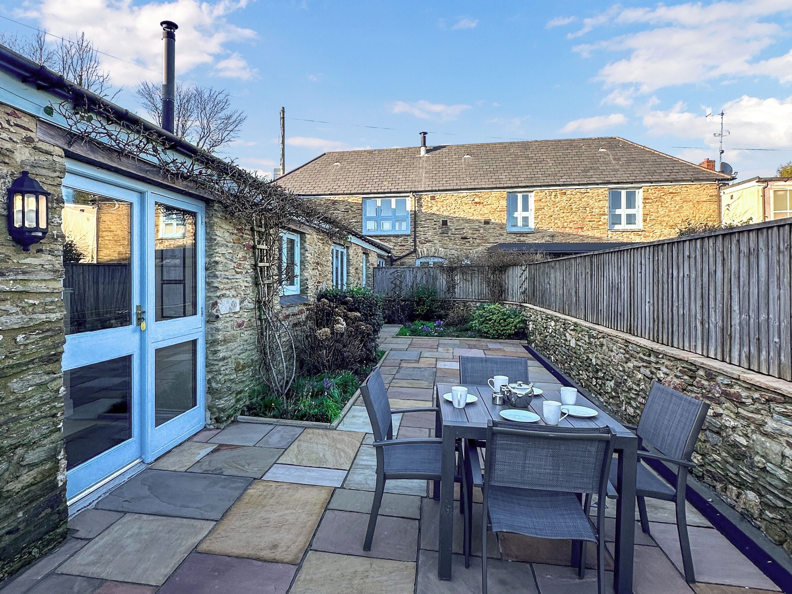Une maison en pierre dotée d’un patio aménagé avec une table dressée pour les repas.