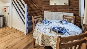 A dining area with a round table, chairs, and a brick wall. - 2 bedroom accommodation in Ledbury (Ledbury)