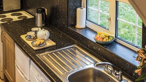 A kitchen with a stainless steel sink, a coffee maker, a tea pot, and a bowl of fruit on the counter. - 2 bedroom accommodation in Ledbury (Ledbury)