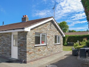 Une maison en pierre avec un toit en tuiles, une cheminée et un petit porche.