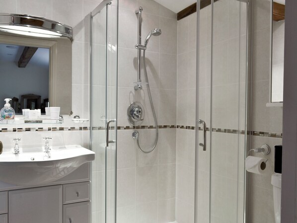 A modern bathroom with a glass-enclosed shower, a white sink with a mirror above it, and a tiled backsplash.