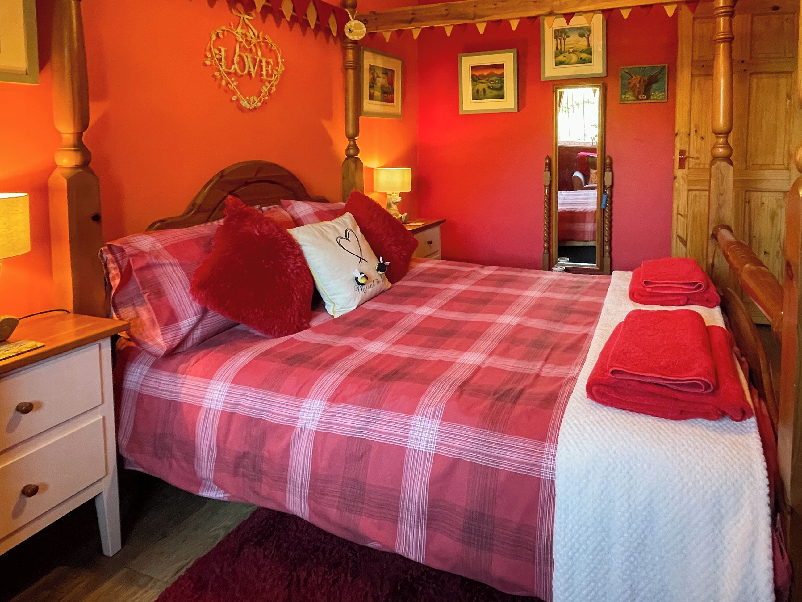 A bedroom with a bed, pillows, a nightstand, a dresser, a mirror, and a door.