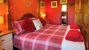 Une chambre à coucher avec un lit, des oreillers, une table de chevet, une commode, un miroir et une porte.