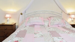 Una cama con dosel, ropa de cama floral y dos lámparas de noche.