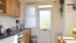 Una cocina compacta con armarios de madera, estufa, lavadora y comedor con mesa y sillas.