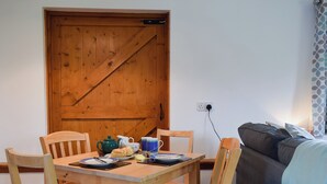 En matplats med ett träbord och stolar, en tekanna, koppar och en tallrik med mat.