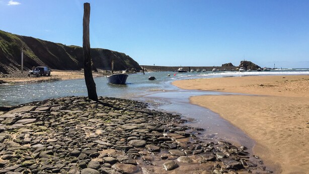 A rocky beach with boats, a sandy shore, and a clear sky. - Perfect for families wanting to holiday together. (Marhamchurch, near Bude)