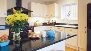A modern kitchen with a central island, a stove, a sink, and light-colored cabinetry. - Perfect for families wanting to holiday together. (Marhamchurch, near Bude)