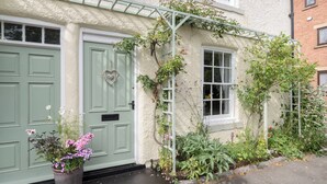 A quaint two-story house with a green door, a heart-shaped decoration, and a window with a white frame. - Brewery House Cottage (Bishop Middleham, near Durham)