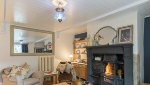 A cozy living room with a fireplace, a sofa, a coffee table with apples, and a mirror on the wall. - Brewery House Cottage (Bishop Middleham, near Durham)