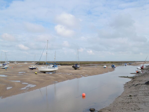 A beach with several boats anchored in shallow water.