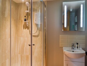 A modern bathroom with a glass-enclosed shower, a white sink, and a mirror above the sink.