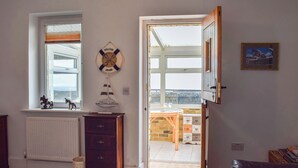 A room with a view through a window, a wooden dresser, a leather sofa, and a door leading outside. - 3 bedroom accommodation in Sandown (Sandown)
