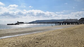 A beach with a pier extending into the water, a sandy shore, and a building labeled 'Sandown Park' in the background. - 3 bedroom accommodation in Sandown (Sandown)