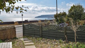 A garden with a wooden fence, stone steps, and a view of the sea. - 3 bedroom accommodation in Sandown (Sandown)