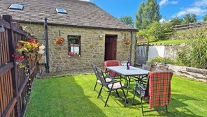 A stone house with a tiled roof, a fenced yard, and a table with chairs. - 3 bedroom accommodation in Salterforth, near Barnoldswick (Salterforth, near Barnoldswick)