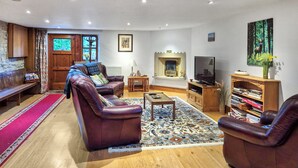 A living room with leather sofas, a wooden coffee table, a fireplace, a television, and a bookshelf. - 3 bedroom accommodation in Salterforth, near Barnoldswick (Salterforth, near Barnoldswick)