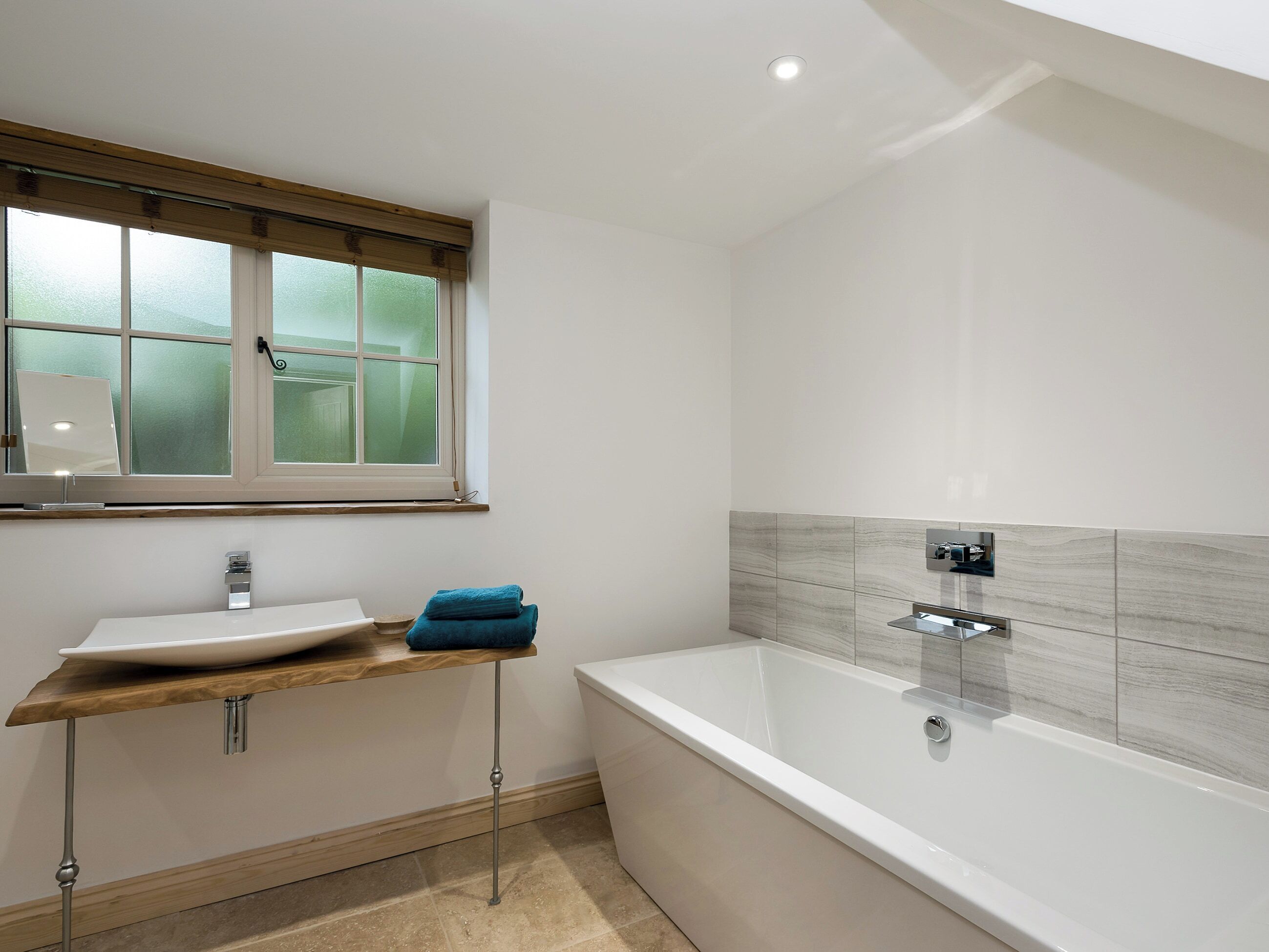 A modern bathroom with a freestanding bathtub, a vanity with a sink, and a window with frosted glass.