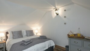 Un dormitorio con cama, mesitas de noche, lámpara, cómoda y bandeja con alimentos para el desayuno.