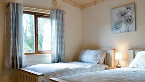 A bedroom with two beds, a window with curtains, a bedside lamp, and a painting on the wall. - 2 bedroom accommodation in Bromlow, near Minsterley (Bromlow, near Minsterley)