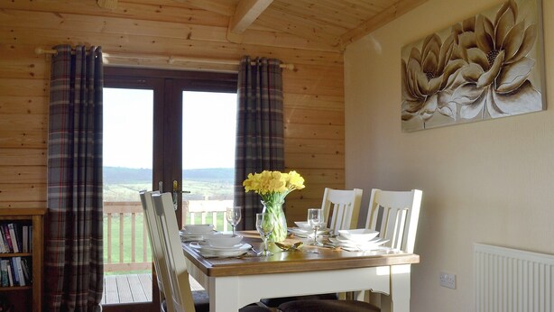 A wooden dining room with a table set for two, a bookshelf, and a view through a glass door. - 2 bedroom accommodation in Bromlow, near Minsterley (Bromlow, near Minsterley)