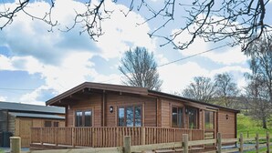 A wooden cabin with a porch, large windows, and a fenced yard. - 2 bedroom accommodation in Bromlow, near Minsterley (Bromlow, near Minsterley)