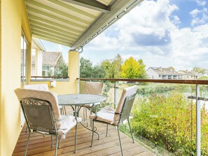 A balcony with a table and chairs, overlooking a body of water and greenery. - 5 bedroom accommodation in Somerford Keynes (Somerford Keynes)