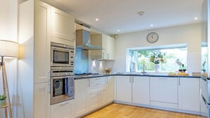 Een moderne keuken met witte kastjes, roestvrijstalen apparatuur en een houten vloer.