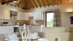 Zona pranzo con tavolo apparecchiato per quattro persone, una bottiglia di vino e vista all'esterno attraverso una finestra.