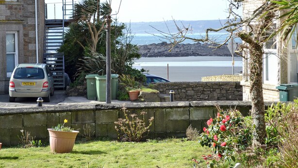 A residential area with a stone wall, a parked car, and a view of the sea. - Most people have heard of St. (Marazion, near Penzance)