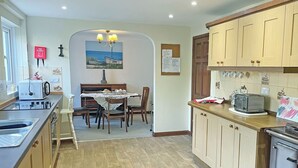 A kitchen with wooden cabinets, a dining table, and a stove. - Most people have heard of St. (Marazion, near Penzance)