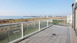 Een balkon met uitzicht op de zee en verre gebouwen.