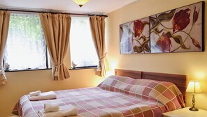 A neatly made bed with a checkered bedspread, a bedside lamp, and a painting of flowers on the wall. - 1 bedroom accommodation in Troutbeck, near Keswick (Troutbeck, near Keswick)