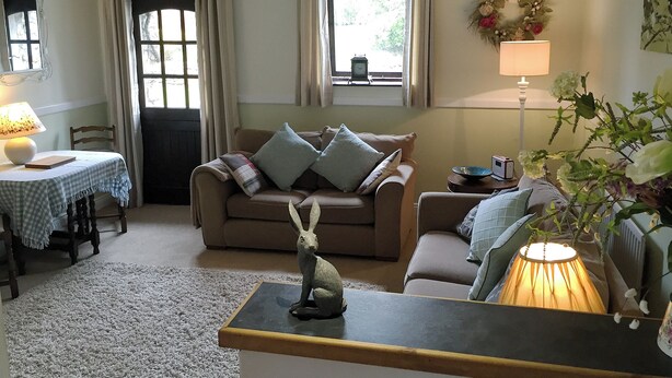 A cozy living room with a sofa, a table with a lamp, and a decorative dog statue. - 1 bedroom accommodation in Troutbeck, near Keswick (Troutbeck, near Keswick)