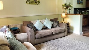A cozy living room with a sofa, a coffee table, and a lamp. - 1 bedroom accommodation in Troutbeck, near Keswick (Troutbeck, near Keswick)