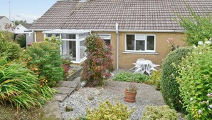 A house with a tiled roof, a conservatory, and a garden with various plants and a gravel path. - 2 bedroom accommodation in Cockermouth (Cockermouth)