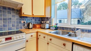 A kitchen with a stove, oven, and a window with a view of the outside. - 2 bedroom accommodation in Harford, Dartmoor National Park (Harford, Dartmoor National Park)