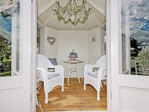 A cozy room with white wicker furniture, a wooden floor, and a ceiling with a decorative chandelier. - 2 bedroom accommodation in Stainton, Penrith (Stainton, Penrith)