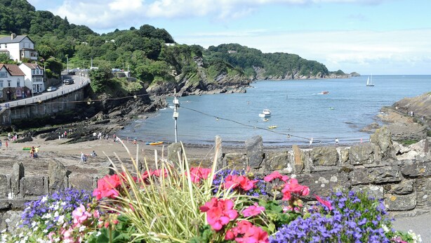 A coastal scene with a stone wall, flowers, and a view of the sea with boats and a sailboat. - 2 bedroom accommodation in Chivenor Cross, near Barnstaple (Chivenor Cross, near Barnstaple)